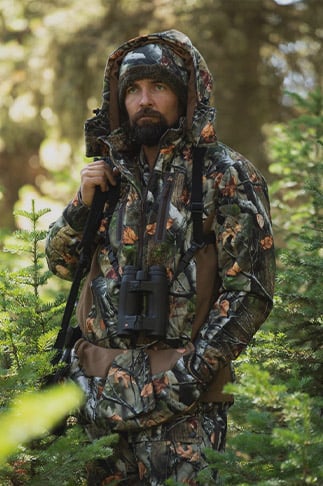 Man in the woods wearing HuntGuard hunting coat and bibs