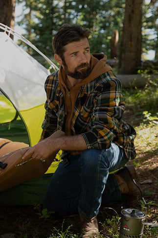 Man camping in the woods wearing a Maplewood Shirt Jacket from Legendary Whitetails
