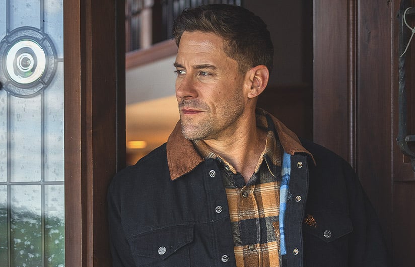 Man standing in a doorway wearing the Men's Concealed Carry Hideout Flannel Lined Canvas Jacket from Legendary Whitetails
