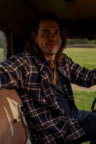 Man sitting in a truck wearing a Buck Camp Flannel Shirt from Legendary Whitetails